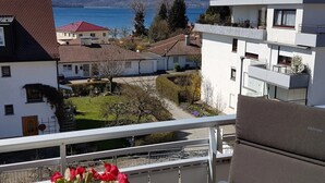 Un balcón con vistas a un lago, edificios cercanos y un jardín.