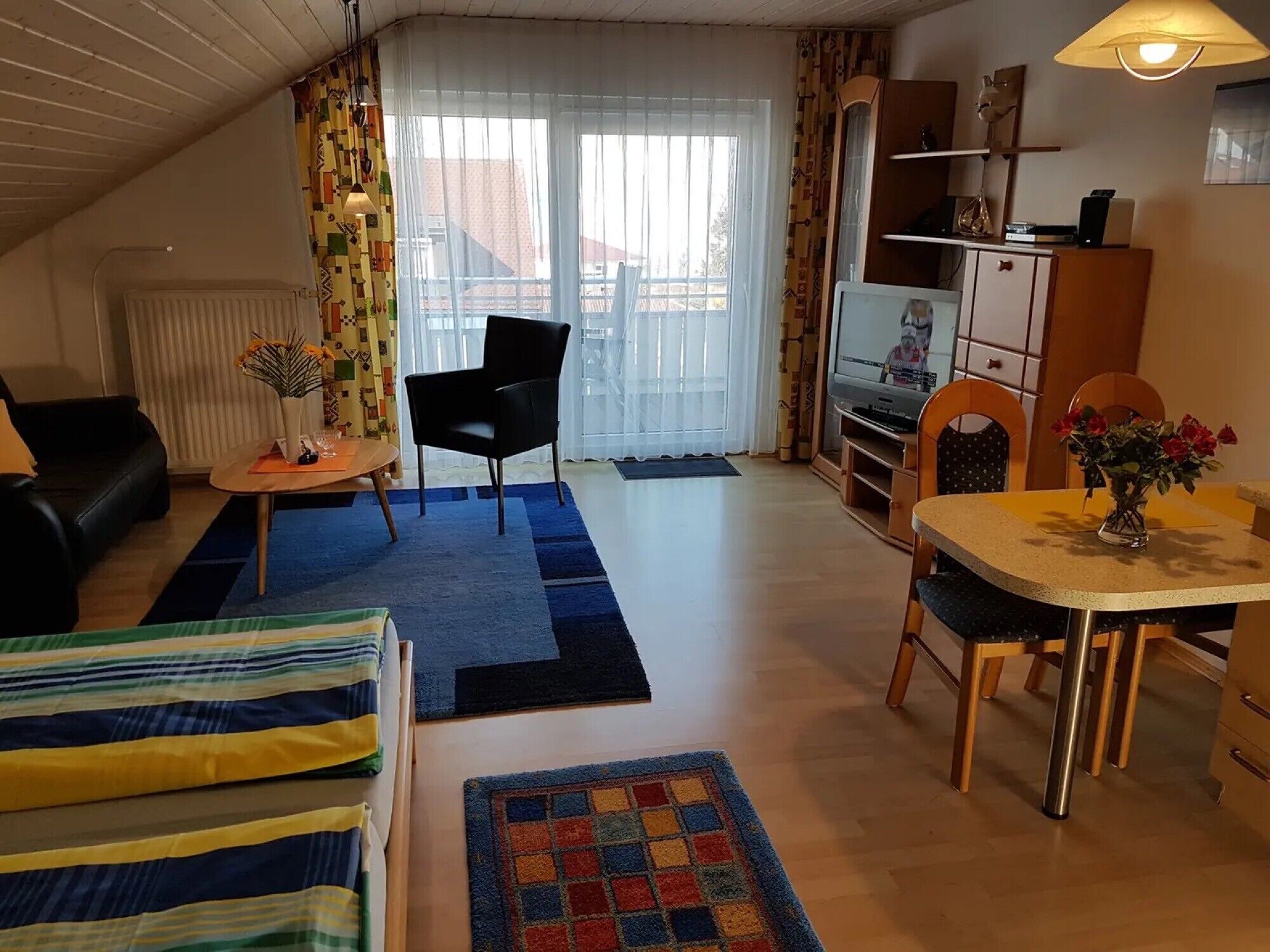 Kodikas olohuone, jossa on sohva, ruokapöytä tuoleineen, televisio ja patteri.