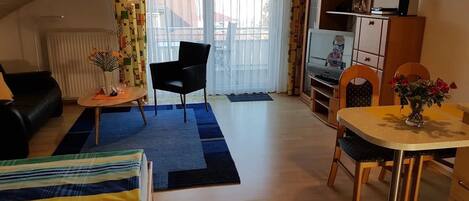 Kodikas olohuone, jossa on sohva, ruokapöytä tuoleineen, televisio ja patteri.