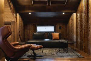 Una habitación acogedora con un sofá de cuero, un sillón de cuero, una mesita y un televisor.