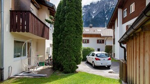 Eine Wohnstraße mit Häusern, einem parkenden Auto und einer hohen Nadelbaumart.
