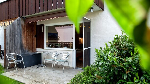 Eine Terrasse mit Sitzgelegenheit, einem Holzzaun und einer weißen Wand.