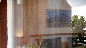 Ein Zimmer mit einem Bett, einer Lampe, einem Gemälde an der Wand und einem Fenster mit Bergblick.