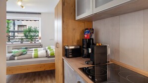 Eine kompakte Küche mit Einbauherd, Kaffeemaschine und Toaster.