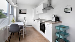 A modern kitchen with white cabinets, a stove, and a coffee maker. - Holiday Home 'Haushälfte Am Süderhafen' with Private Terrace, Private Garden and Wi-Fi (Nordstrand)
