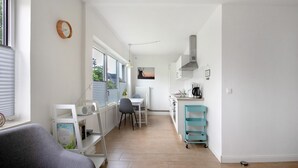 A modern kitchen with a dining area, a clock on the wall, and a view of the outdoors. - Holiday Home 'Haushälfte Am Süderhafen' with Private Terrace, Private Garden and Wi-Fi (Nordstrand)