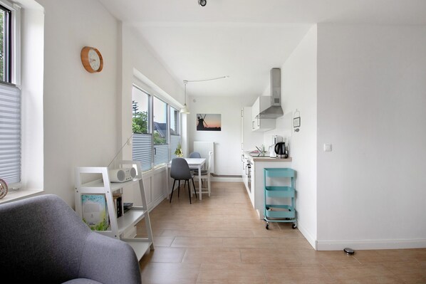 Une cuisine moderne avec un coin repas, une horloge au mur et une vue sur l’extérieur.