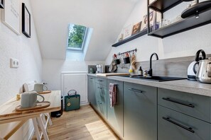 A compact kitchen with a window, a sink, and a kettle.