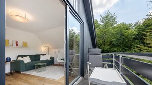 A modern living room with a sofa, a coffee table, and a balcony with a railing. - Apartment with Balcony and Wi-Fi (Lüneburg)