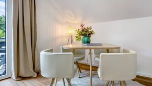 A room with a round table, four chairs, a lamp, a vase with plants, and a window with curtains. - Apartment with Balcony and Wi-Fi (Lüneburg)