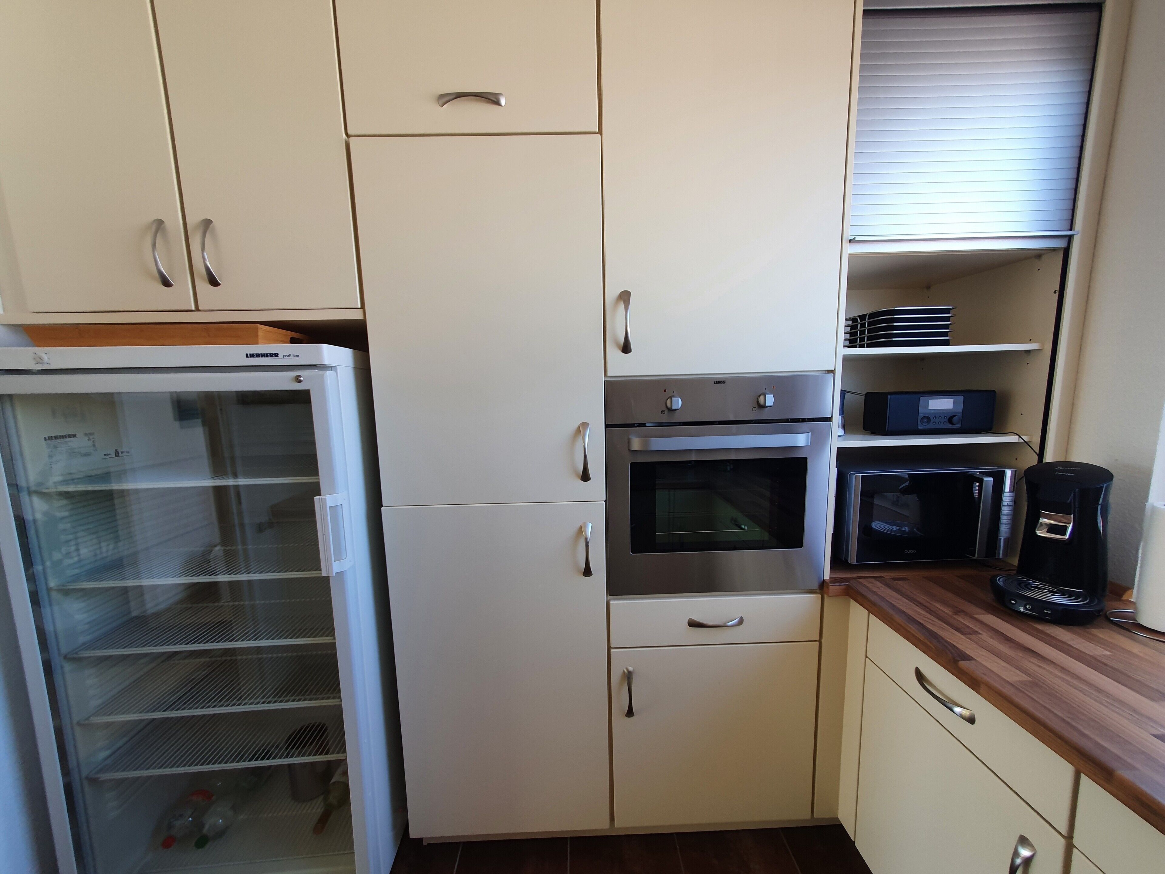 Eine Küche mit Kühlschrank, Backofen, Mikrowelle und Kaffeemaschine.