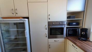 Eine Küche mit Kühlschrank, Backofen, Mikrowelle und Kaffeemaschine.