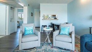 Un salón con dos sillones, una mesita y vistas a la cocina.