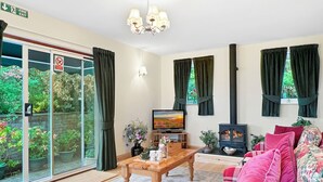 A living room with a television, a fireplace, a sofa, and a table with a vase of flowers.
