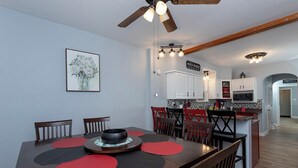 A dining area with a wooden table, red placemats, and a ceiling fan. - River House - Harrisburg City Skyline Views with Game Room and Covered Porch (Wormleysburg)