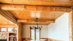 A wooden interior with a round table and chairs, a fireplace, and a stone shelf. - Lakefront Cabin on LCO - The Sunset Escape (Hayward)
