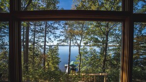 A window with a view of a forest and a lake. - Lakefront Cabin on LCO - The Sunset Escape (Hayward)