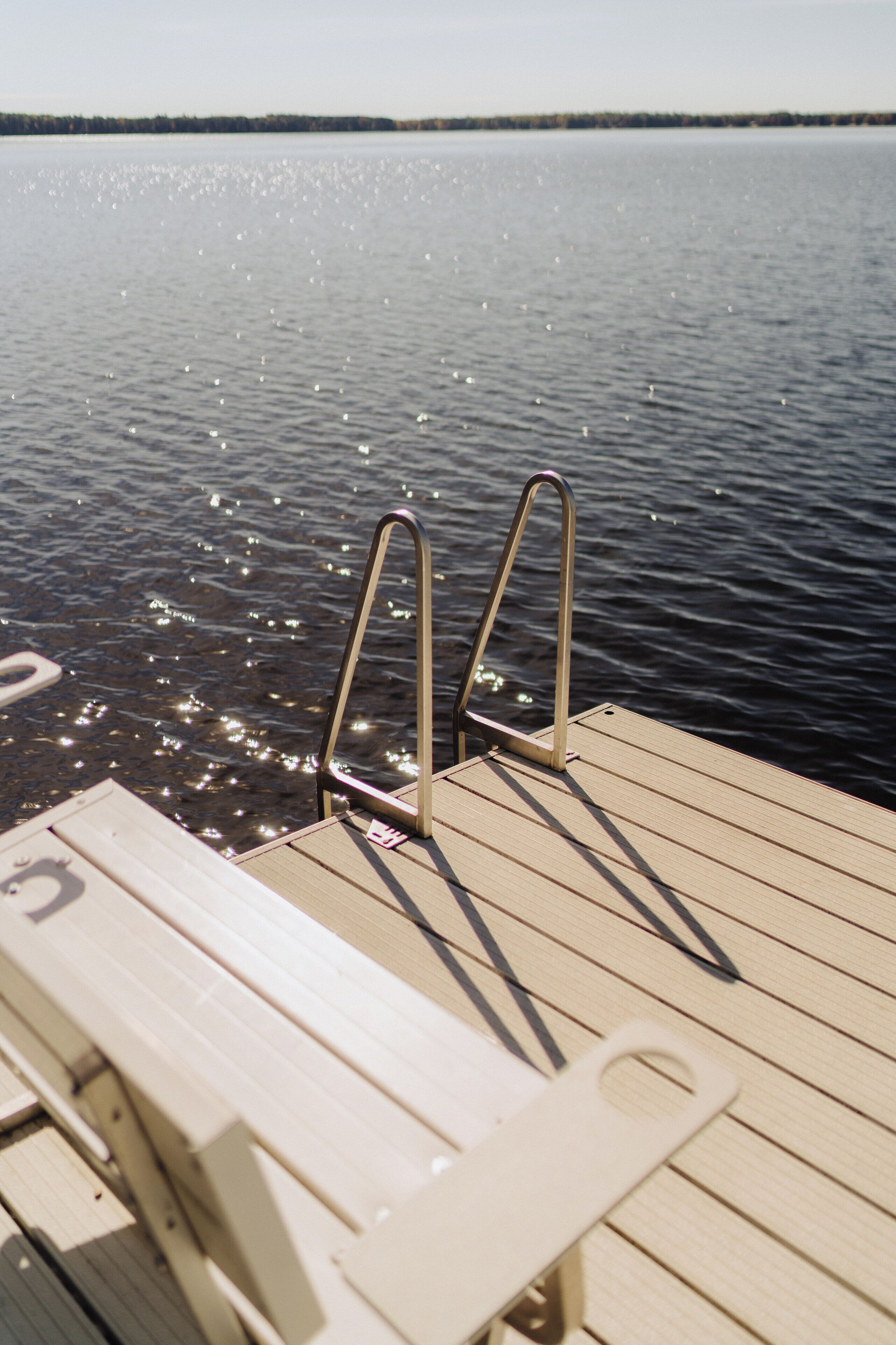 Une jetée en bois, dotée de rampes métalliques, s’étend au-dessus d’une étendue d’eau calme.