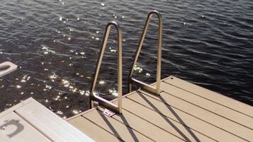 Une jetée en bois, dotée de rampes métalliques, s’étend au-dessus d’une étendue d’eau calme.