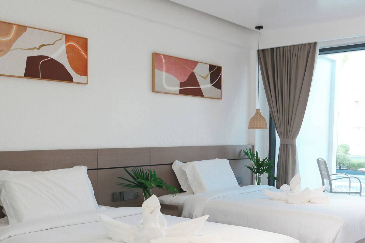 A modern hotel room with two beds, white linens, a large window with curtains, and abstract wall art.