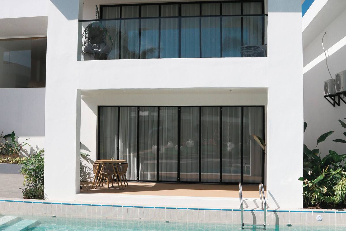 A modern two-story building with a swimming pool in front.
