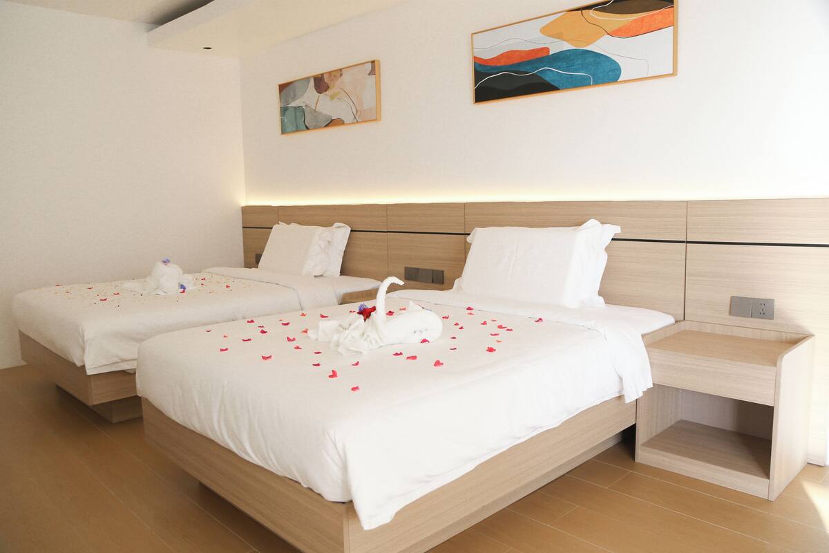 A hotel room with two beds, a wooden headboard, and a nightstand.