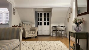 Un salón con un sillón a rayas, un sofá, una mesa de comedor con sillas y un jarrón con flores sobre una consola.