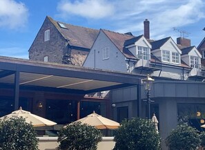 A covered outdoor area with umbrellas, stone buildings, and a modern structure. - Apartment Sleeps 2 with Wi-Fi (Ludlow)