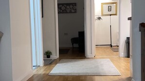 Un pasillo con alfombra, suelo de madera y una puerta que da a otra habitación.