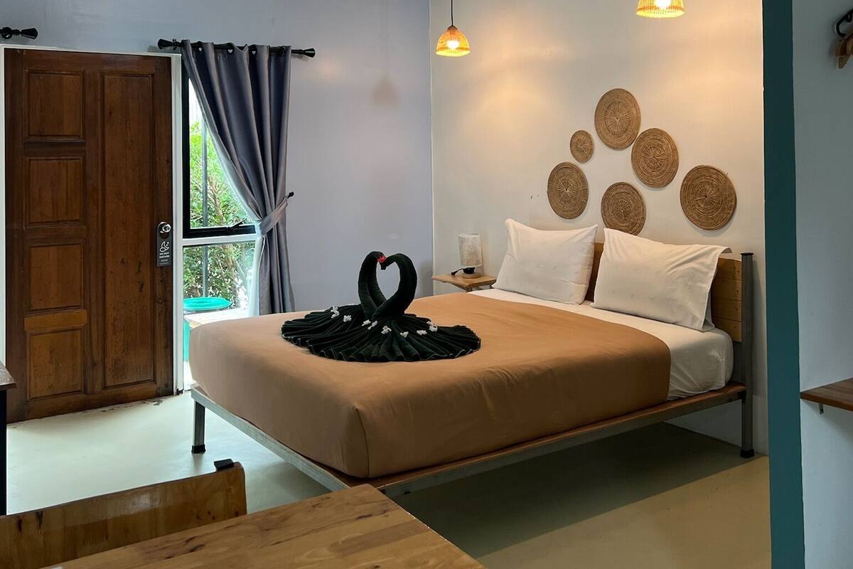 A modern bedroom with a bed, wooden headboard, wall-mounted air conditioner, and decorative woven wall art.
