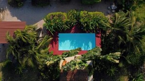 An aerial view of a resort with four red-roofed buildings, a central swimming pool, and lush tropical vegetation. - The Canopy Krabi (Krabi)