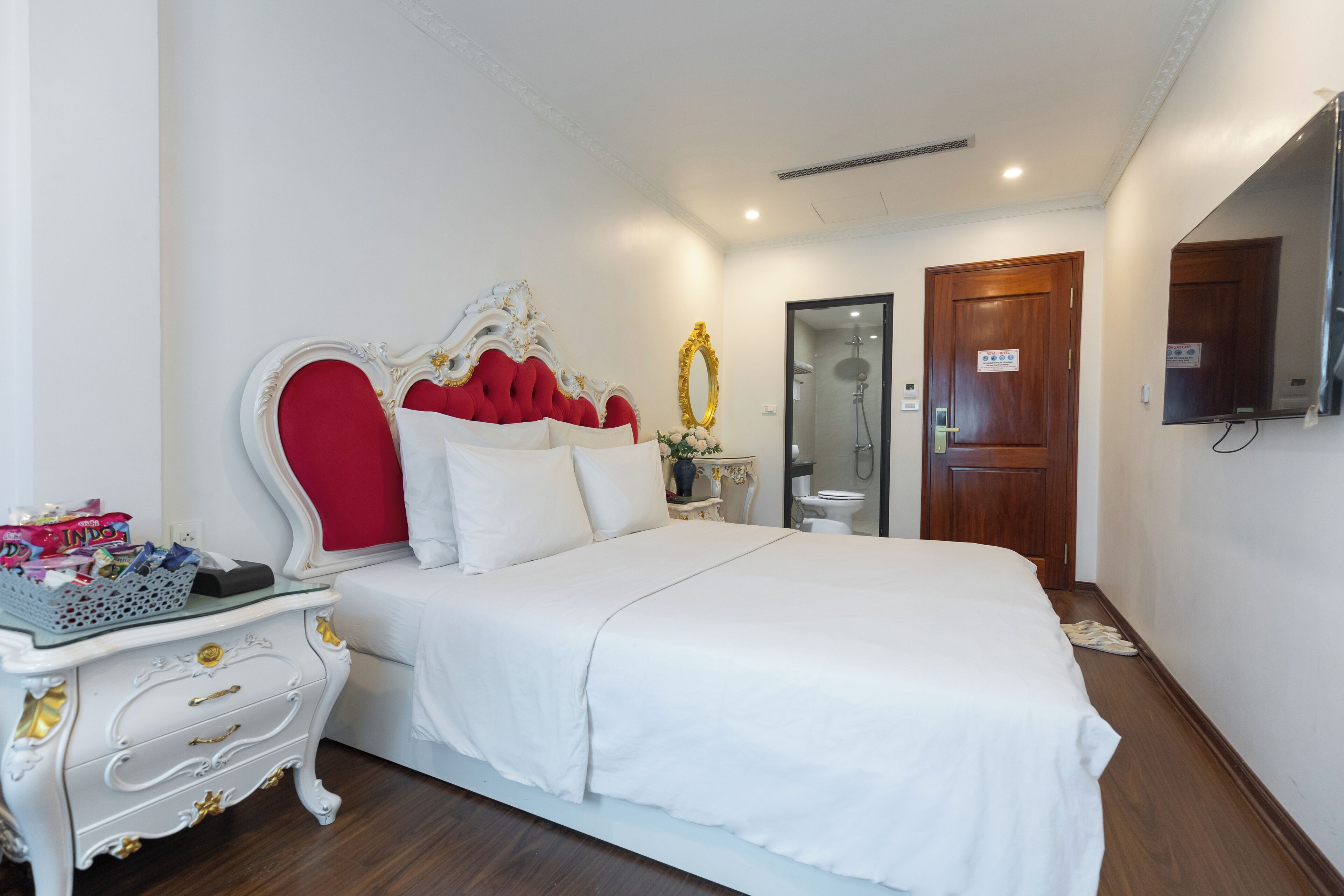 A neatly arranged bedroom with a large bed, a bedside table, and a mirror.