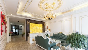 A luxurious room with a green sofa set, a large potted plant, and a marble floor. - Royal Hotel Thanh Tri (Hanoi)