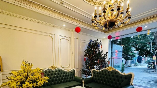 A luxurious lobby with a grand chandelier, a Christmas tree, and a seating area with a coffee table and ottomans. - Royal Hotel Thanh Tri (Hanoi)
