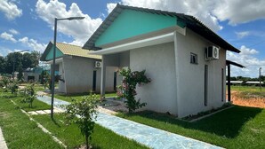 Une maison moderne à deux étages, dotée d’un toit végétalisé, d’un porche abrité et d’un petit jardin agrémenté de fleurs roses.
