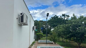 Un chemin mène à un espace piscine, avec un bâtiment blanc d’un côté.