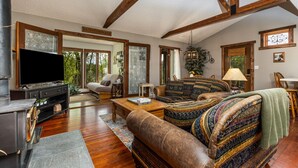 A spacious living room with a large flat-screen TV, a comfortable sofa, and a wooden coffee table.