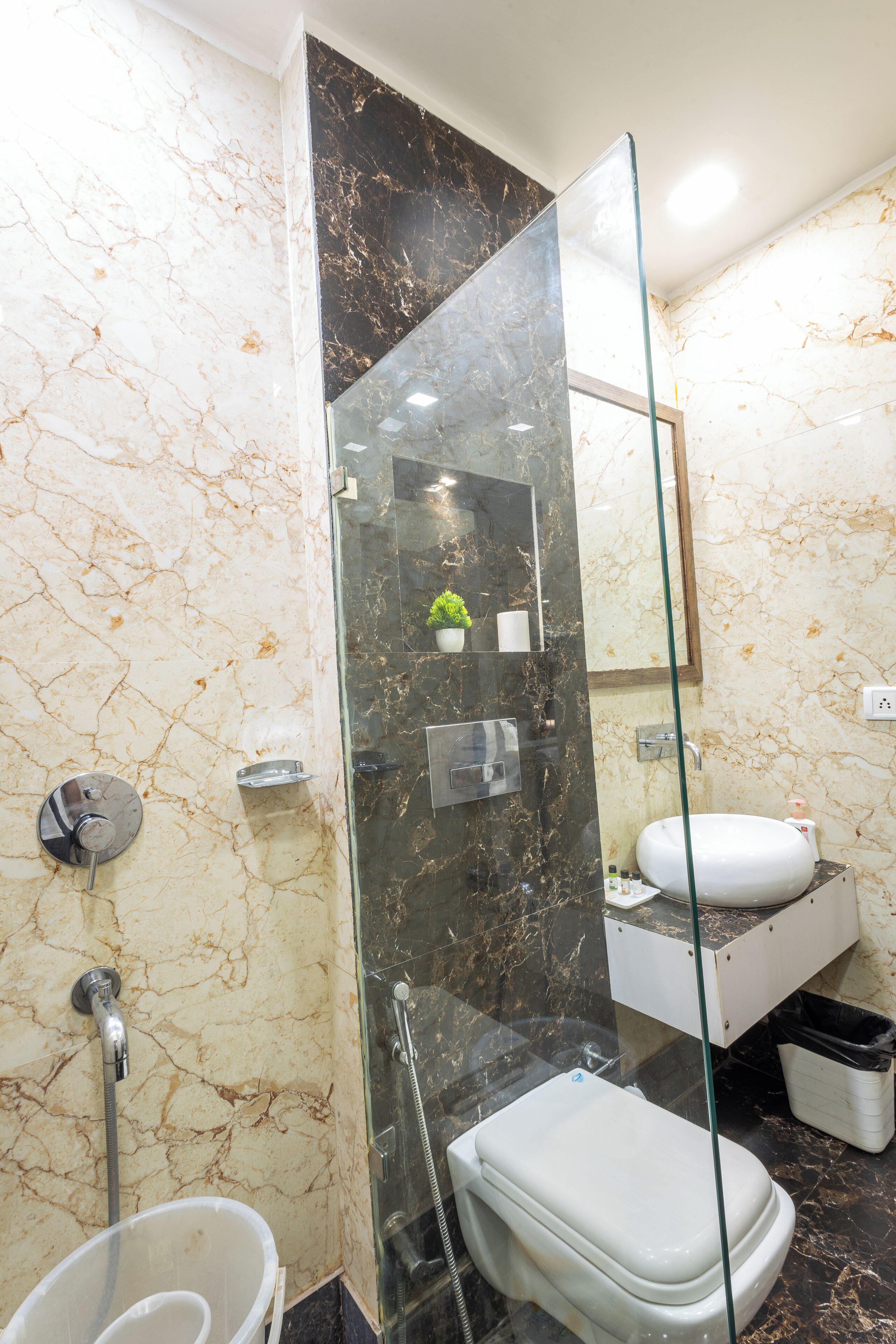 A modern bathroom with a glass-enclosed shower, a white toilet, and a marble wall.
