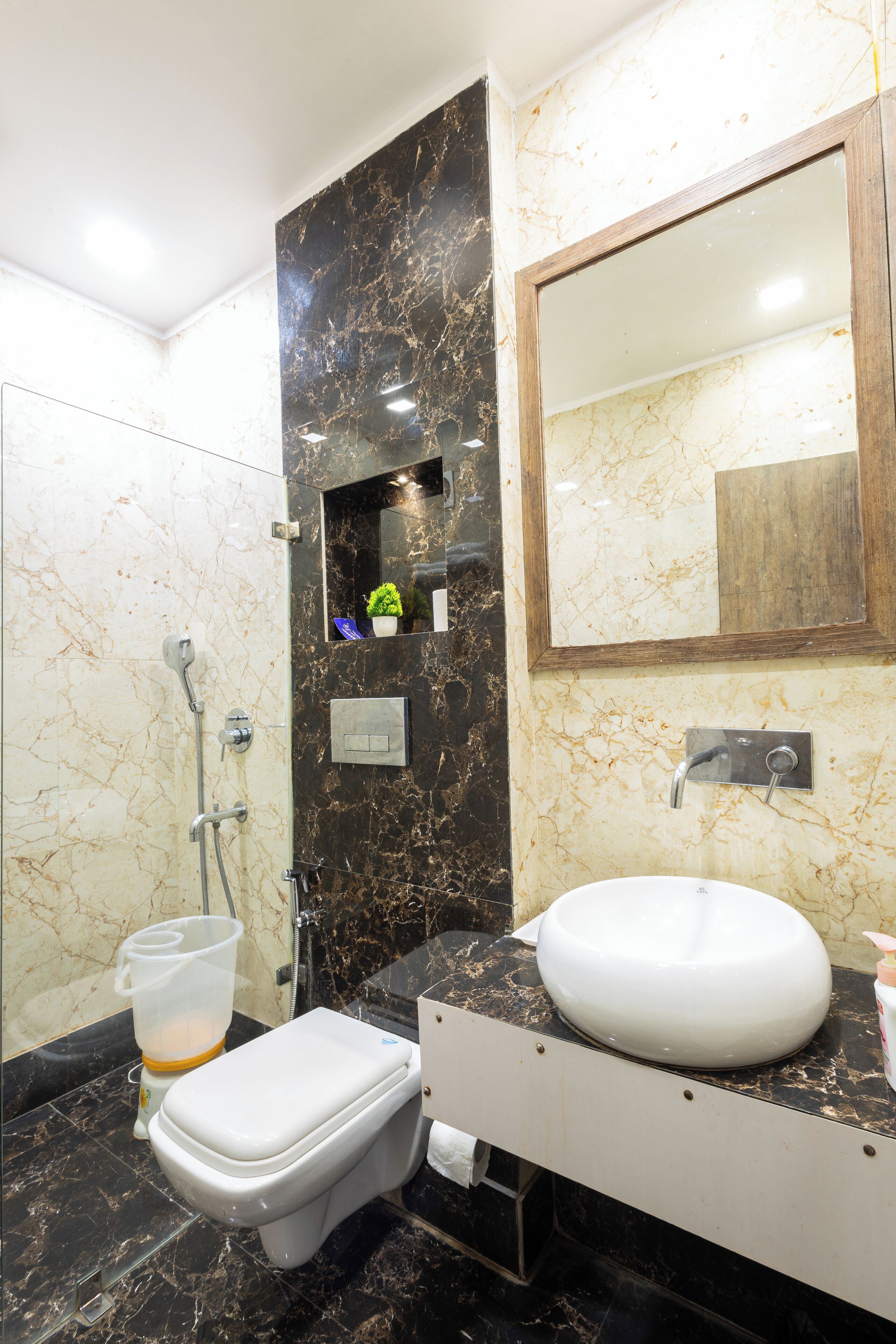 A bathroom with a toilet, sink, mirror, and shower.