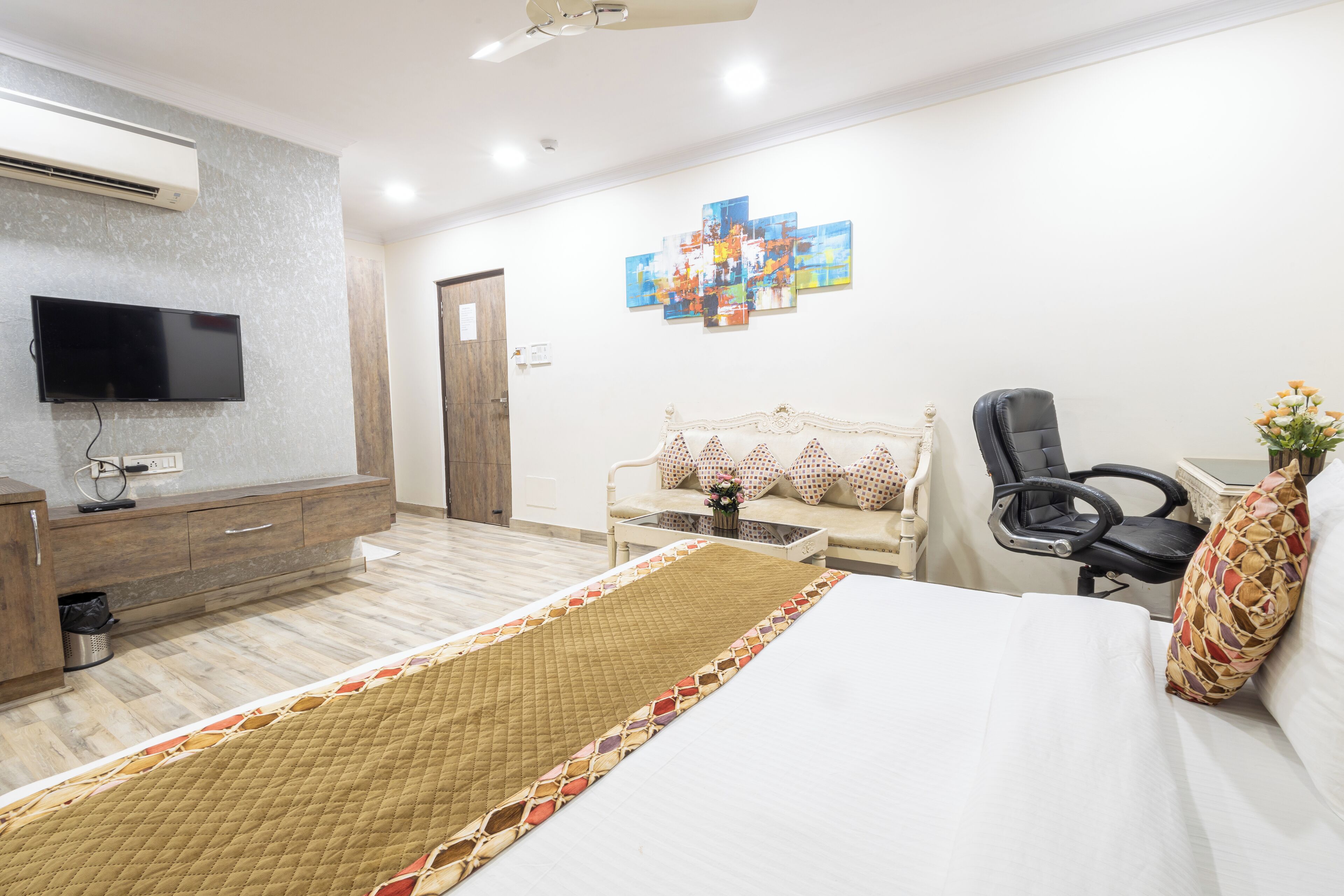 A hotel room with a bed, a TV, a desk, and a chair.