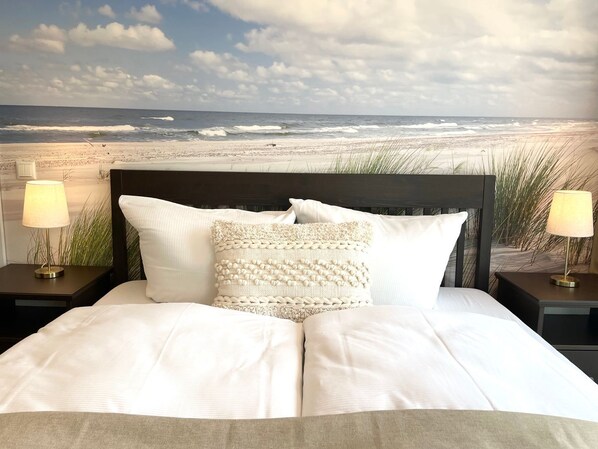 A bed with a view of the beach and ocean.