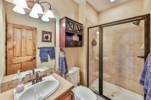 Une salle de bain avec un grand miroir, un lavabo, des toilettes et une douche à parois de verre.