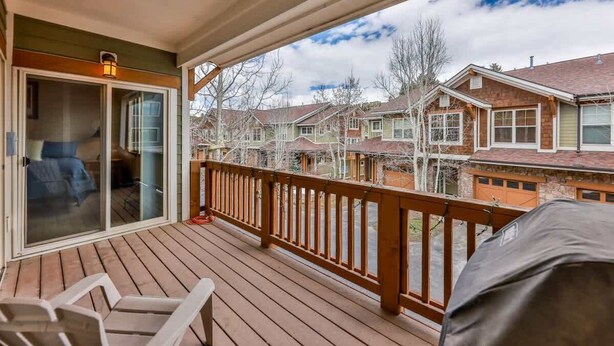 A wooden deck with a railing, a covered seating area, and a view of neighboring houses.