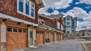 A row of modern townhouses with attached garages, a clear sky, and a well-maintained driveway.