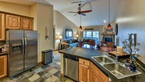A modern kitchen with a central island, stainless steel appliances, and a dining area with a sofa and table.