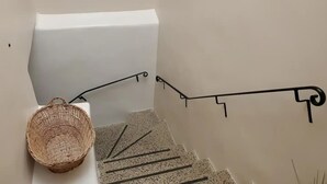 Una escalera con una cesta tejida a la izquierda y una barandilla de metal negro.
