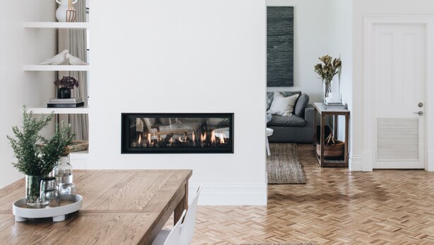 Een moderne woonkamer met een open haard, houten vloeren en een witte deur.