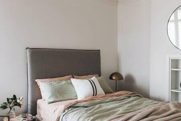 A bedroom with a bed, pillows, a bedside lamp, and a nightstand.