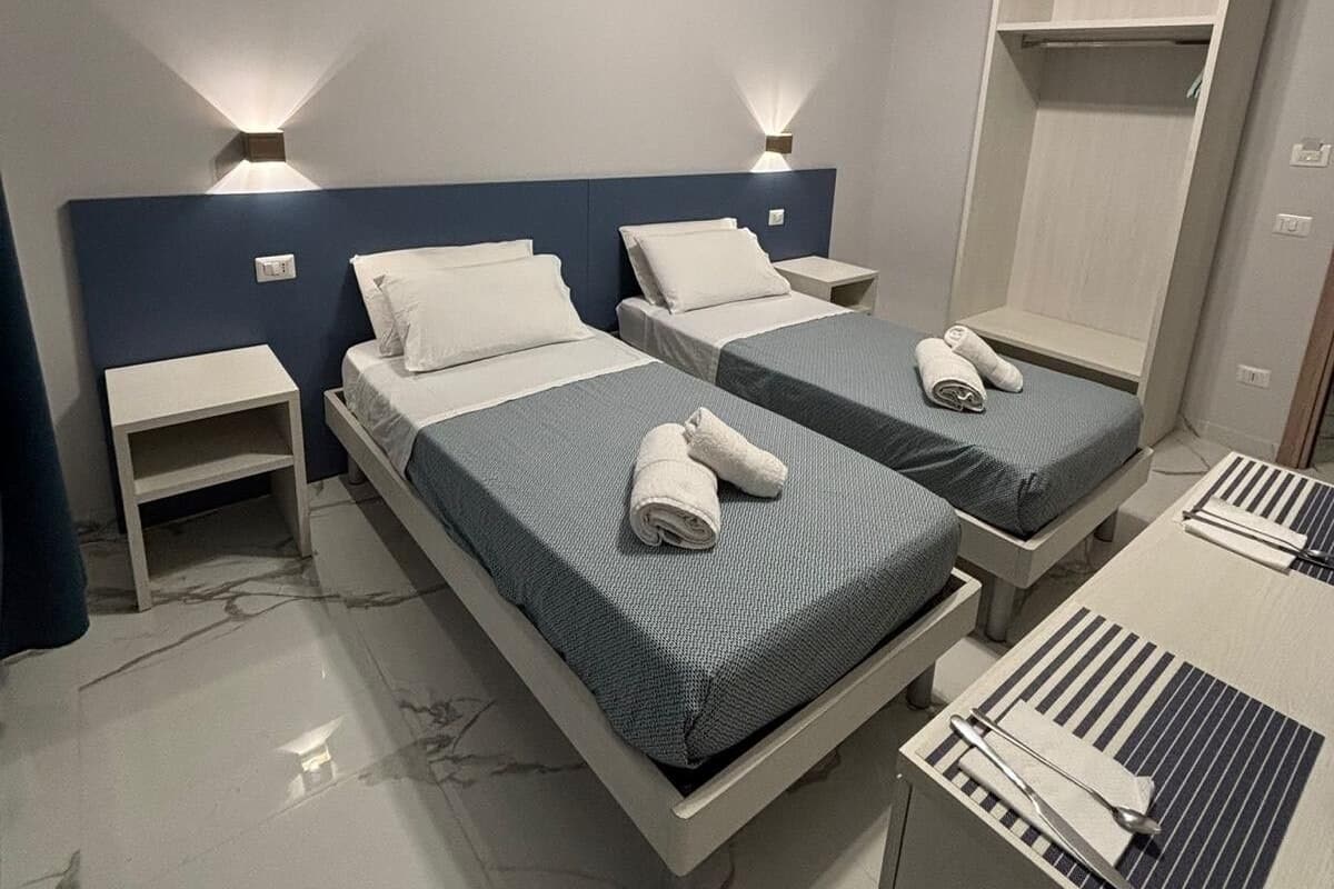Habitación de hotel con dos camas, un escritorio y un armario.