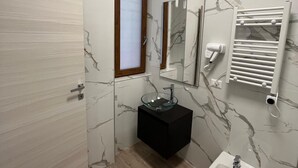 A bathroom with a marble wall, a black vanity, a glass sink, a bidet, and a towel rack. - B&B CADIFRA PORTAPICCOLA (Naples)